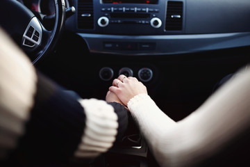 Inside the car, a loving couple holds hands. The guy and the girl on the road are traveling