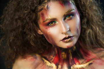 Fototapeta premium beautiful curly girl in a fire makeup and green shadows under the cloak image created by a make-up artist