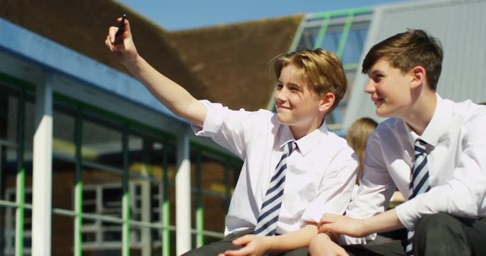 4K Happy preteen schoolboy friends pose to take a selfie outside school building. Slow motion