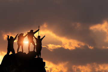 Businessman and women group hike on the peak of silhouette rocks mountain at sunset, success, winner and leader concept .
