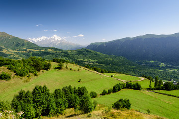 Fototapeta na wymiar Beautiful natural landscape with green meadows. The mountains in the background. The village of Mestia, Svaneti, Georgia.