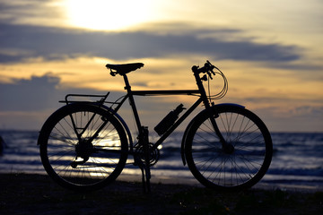 Side view of Silhouette bicycle with Sunset on the beach .