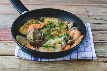 Hake with prawns and clams in frying pan.