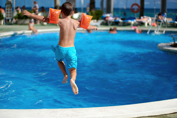 Naklejka premium Caucasian boy having fun jumping into the pool.