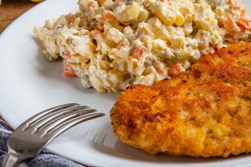Fried pork chop in breadcrumbs, served with vegetable salad.