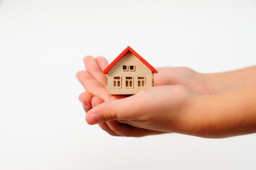 Fototapeta na wymiar Child hands holding model of house on wite background. Adoption concept.