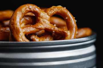Crunchy pretzels appetizer in a metal jar on a black table. Mystic light style.