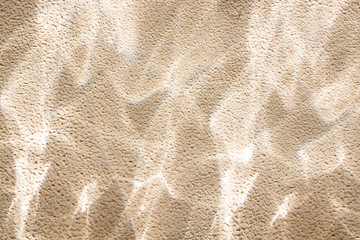 Curved glare of light on the textured wall.