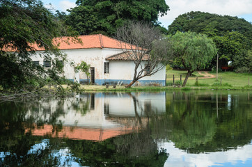 Fototapeta na wymiar típica paisagem do interior do Brasil com um lago e uma casa ao fundo