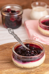 Cheesecake in glass jar with cookies and berries.