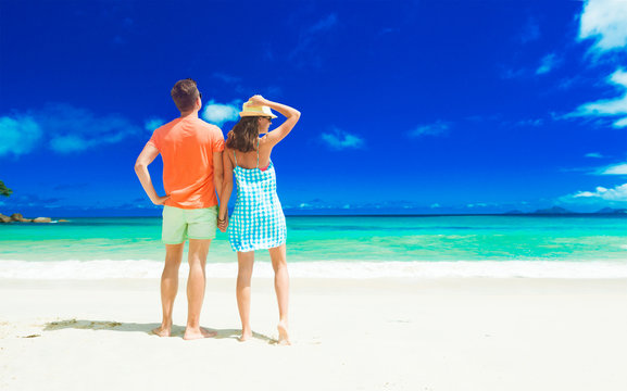 Couple in bright clothes on a tropical beach at Mahe, Seychelles.
