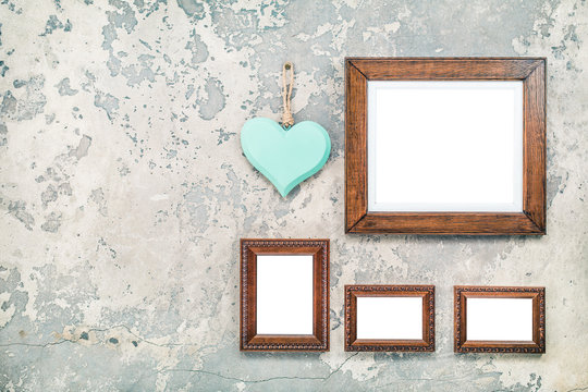 Wooden photo or picture frames blanks and handmade Valentine's day love heart hanging on vintage aged grunge textured concrete wall background. Retro old style filtered photo