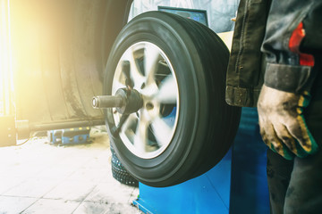 Wheel balancing or repair and change car tire at auto service garage or workshop by mechanic