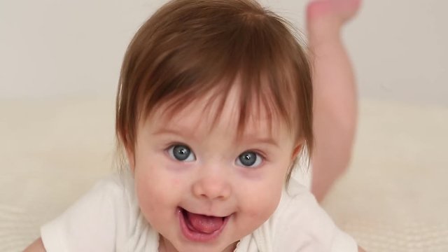 Portrait of adorable 3 month old baby girl with big blue eyes lying on the tummy.