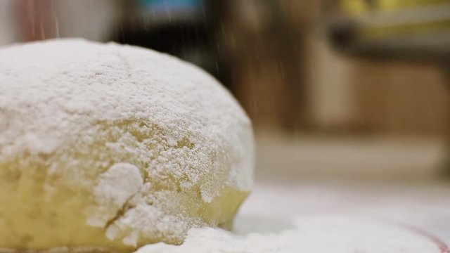 Close-up view of the dough ball for homemade pasta strewing with flour. Pasta cooking process.