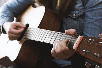 Young girl playing acoustic guitar with jeans shirt