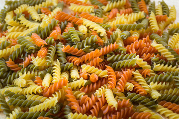 Uncooked three-colored italian pasta. Dried italian pasta on a wooden table.Colored natural pasta