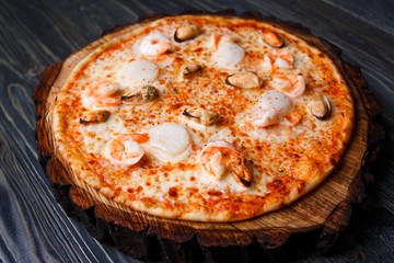 Fresh delicious seafood pizza with shrimps and mussels served on wood, close up. Delicious Italian food