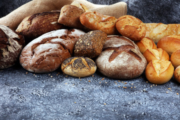 Different kinds of bread and bread rolls on board from above. Kitchen or bakery poster design