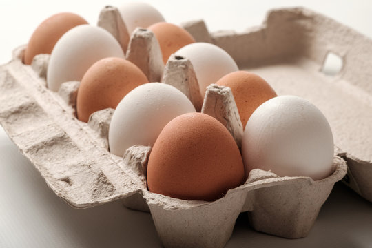 White and brown chicken eggs in a cardboard package.