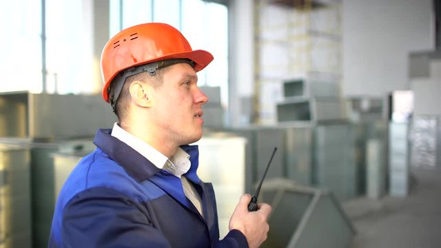 Engineer builder using a walkie talkie giving instructions at a construction site inside. 4 k