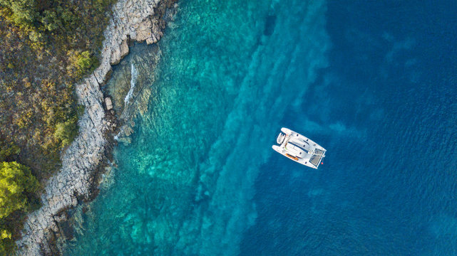 Aerial view of anchoring catamaran next to island.