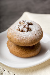 Honey biscuits with a core of walnuts on a white plate. Biscuits with powdered sugar. Dark background
