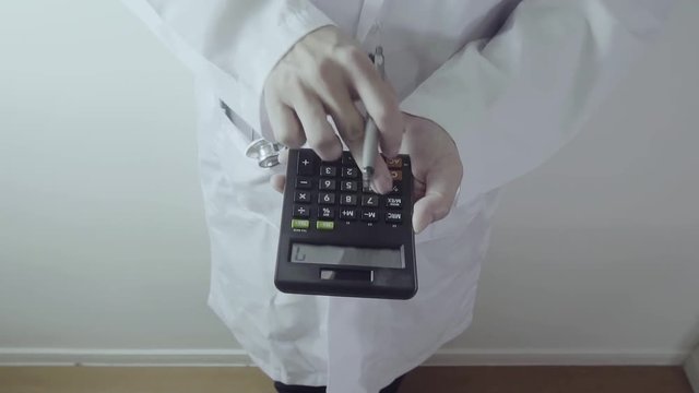 Healthcare costs and fees concept.Hand of smart doctor used a calculator for medical costs in modern hospital