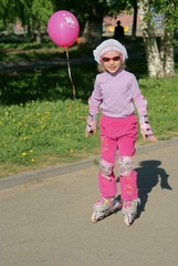Little girl with pink balloon riding on roller blades