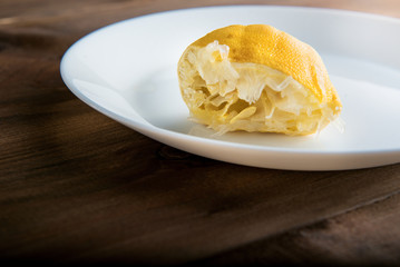 the squeezed-out lemon on a white plate on a wooden background