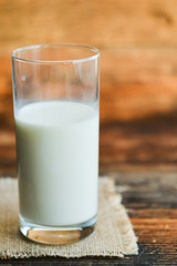 glass of milk with napkin on old wooden table