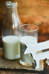 milk bottle, glass of milk, a figure of a cow the concept of a village power, farm-fresh products on a natural wooden background