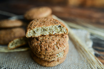 fresh homemade oatmeal cookies on wooden background with spikes of oats