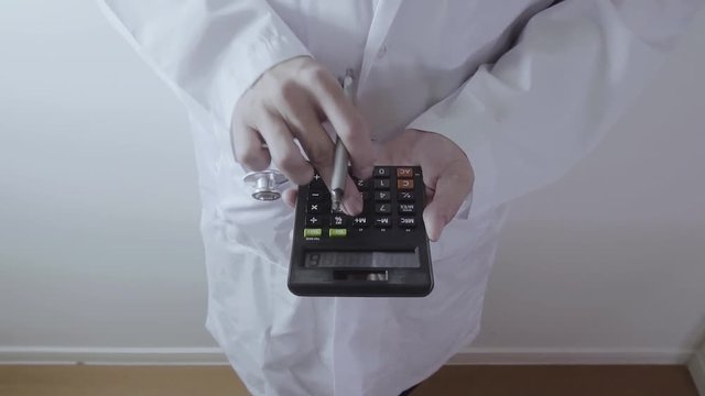 Healthcare costs and fees concept.Hand of smart doctor used a calculator for medical costs in modern hospital