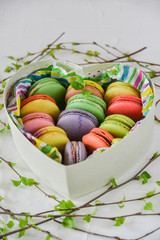 multicolored macaroons in a heart shaped gift box on a white background