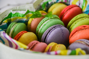 colorful macaroons in a gift box with a bright paper on a light background