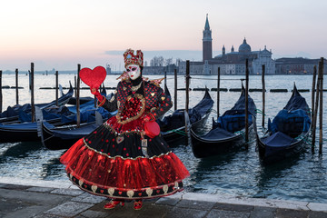 Wonderful costume in black and red with red heart in front of San Giorgio Maggiore, Venice, Carnival