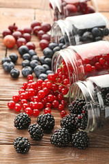 Ripe and sweet berries in bottles on wooden table