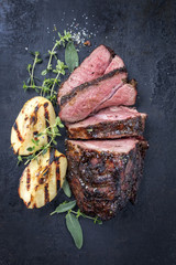 Barbecue roast boar with quinces as top view on a board