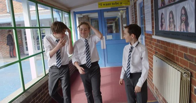 4K Happy young boys walking through school building laughing & teasing each other.