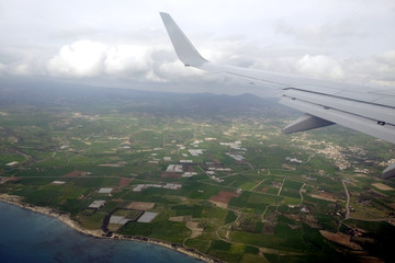 View from the top to the seacoast in the summer season from supersonic plane flying above the sea in the sky with clouds