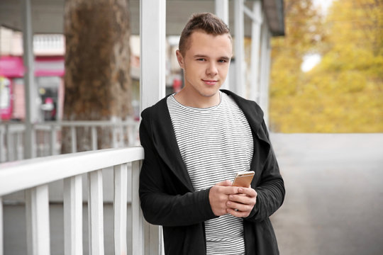 Portrait of hipster teenager with phone outdoors