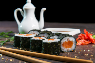 Sushi rolls served on a wooden plate in a restaurant. Sushi rolls and caviar on black wooden table. Japanese food.