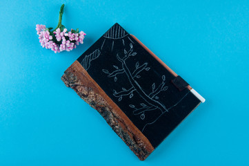 Top view on chalk drawings on small blackboard and bouquet of pink flowers laying on blue background