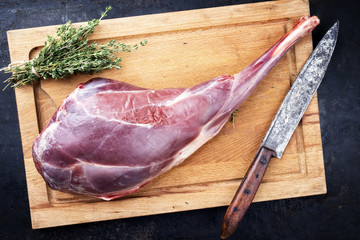 Raw haunch of venison with bone as top view on a cutting board