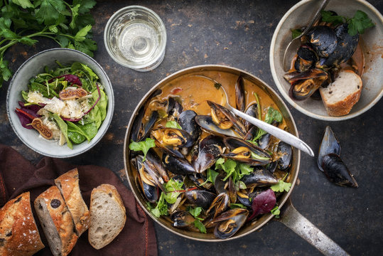 Traditional French blue mussel in bouillabaisse with lettuce and baguette as top view in a casserole