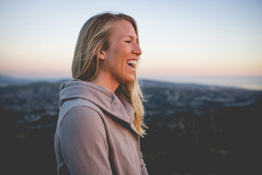 Side view of smiling woman standing against sky during sunset