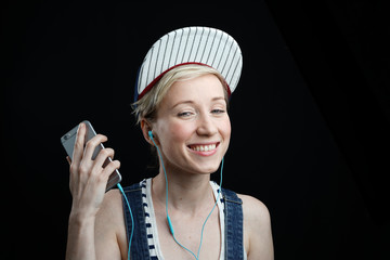 girl in baseball cap listening to music on black background