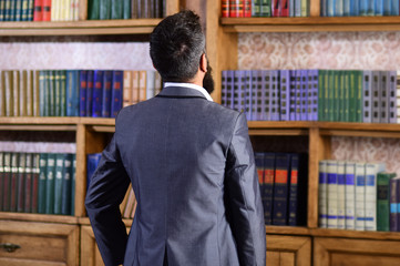 Back view, man near multi colored bookshelf