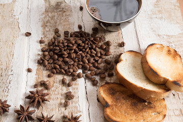 coffee cup, coffee beans of toast scattered on the rough wooden surface background